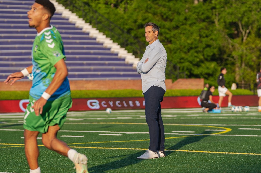 Head Coach John Harkes looks on as players warm up.