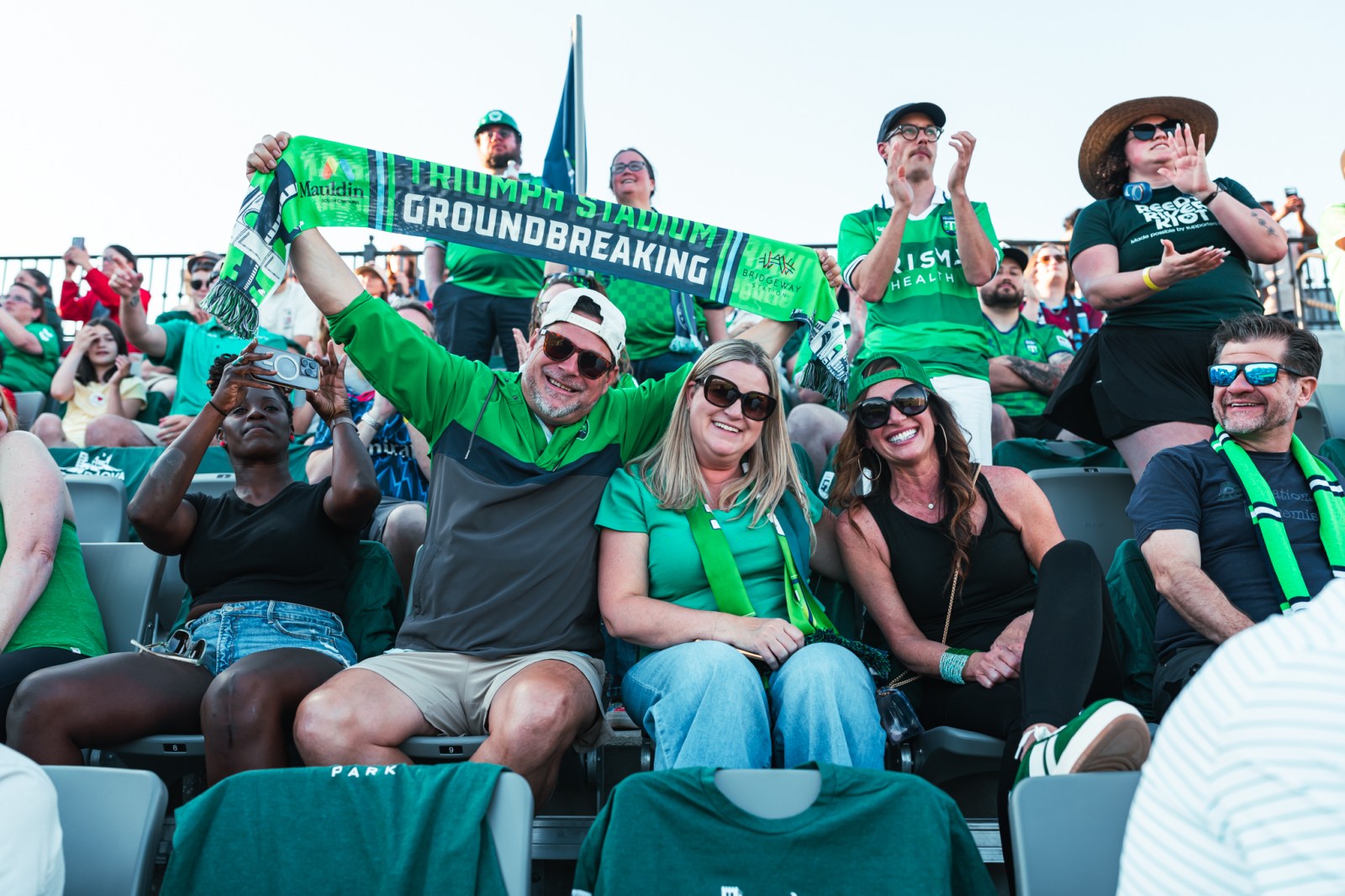 Triumph supporters in green holding scarves in the stands