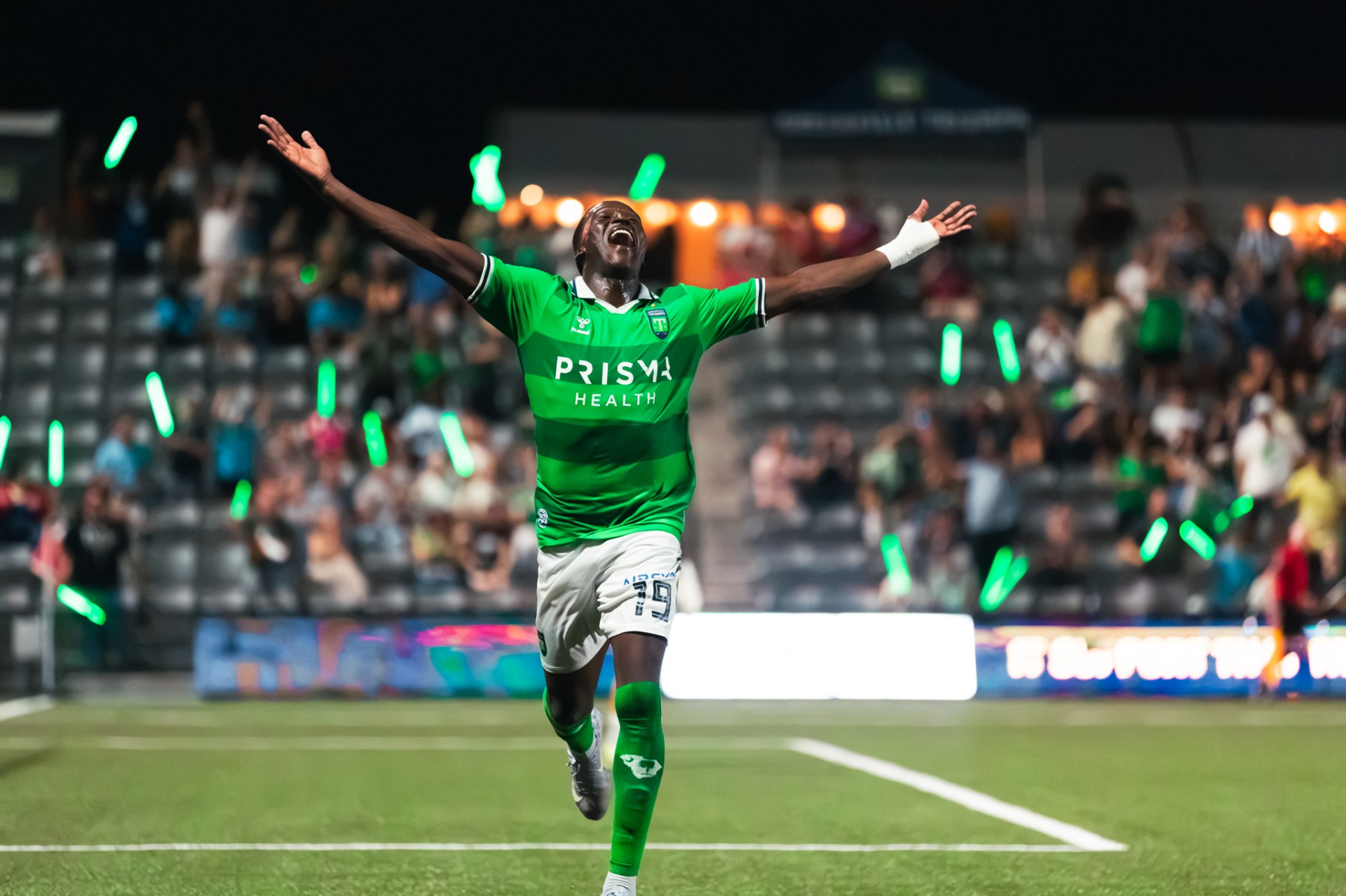 A Triumph player celebrating a goal in front of the stands