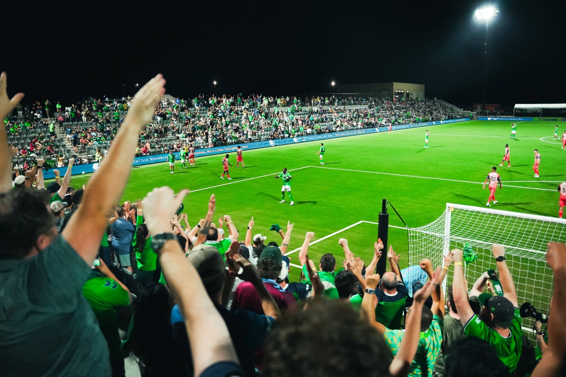 Triumph fans cheering at the front of the stands during a night match